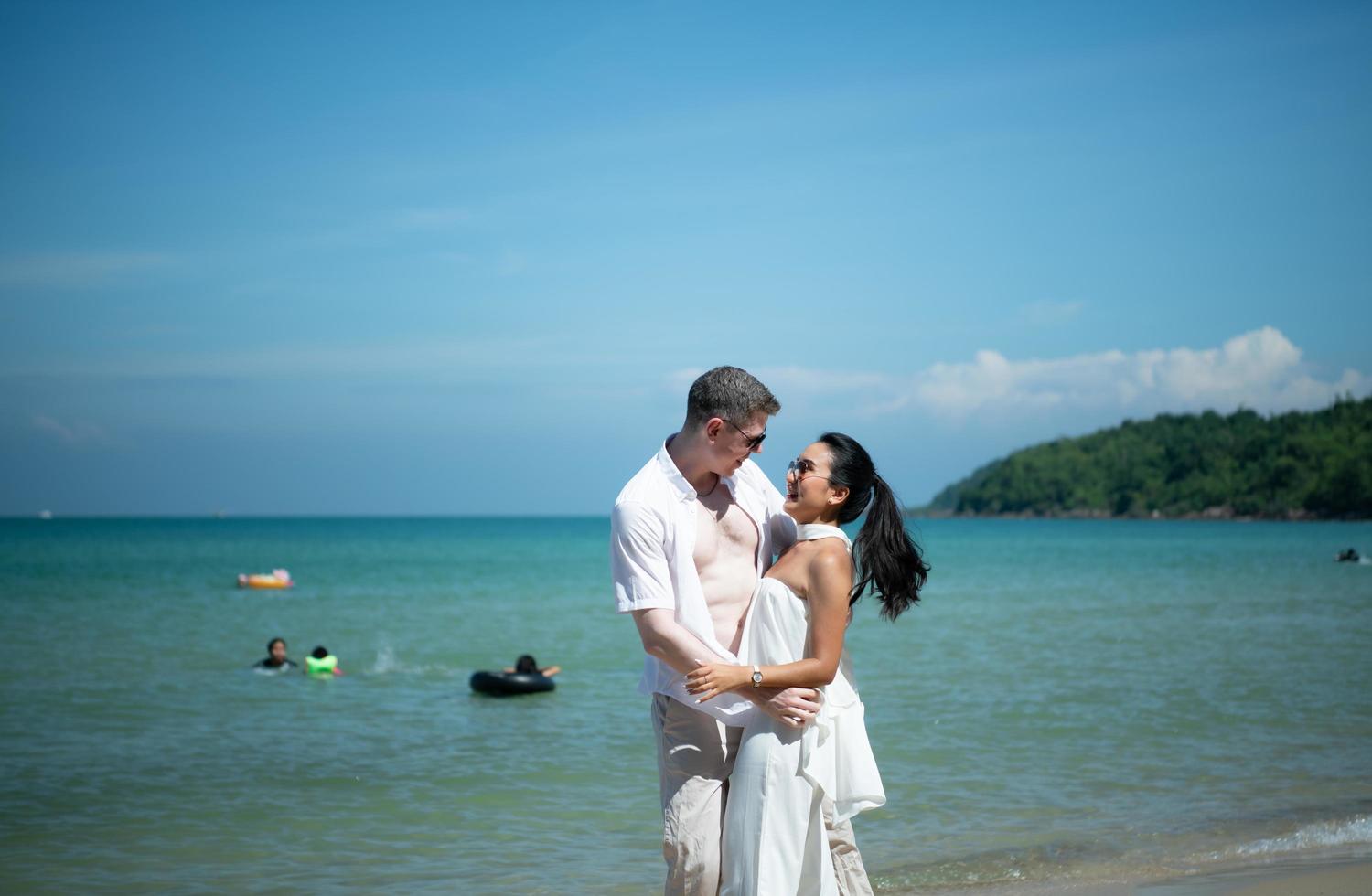 interrassisches Paar mit der Freude, zum wunderschönen blauen Meer wie ins Paradies zu reisen foto