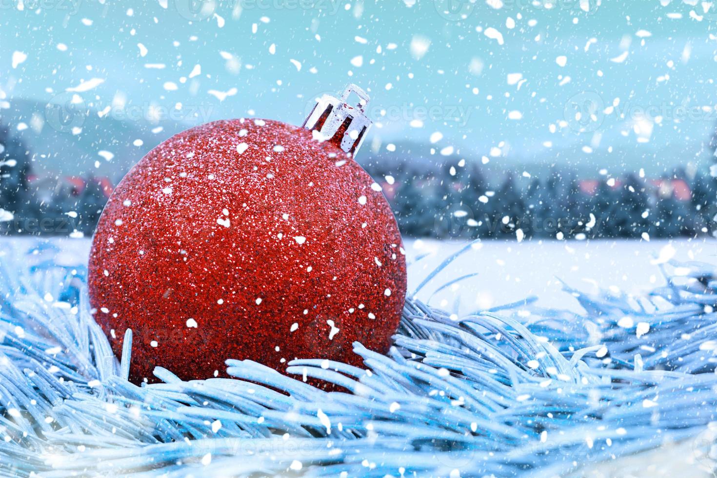 Roter, glänzender Weihnachtsball auf Tannenzweigen, mit verschwommenem Hintergrund und fallendem Schnee. weihnachten, neujahr. Platz kopieren foto