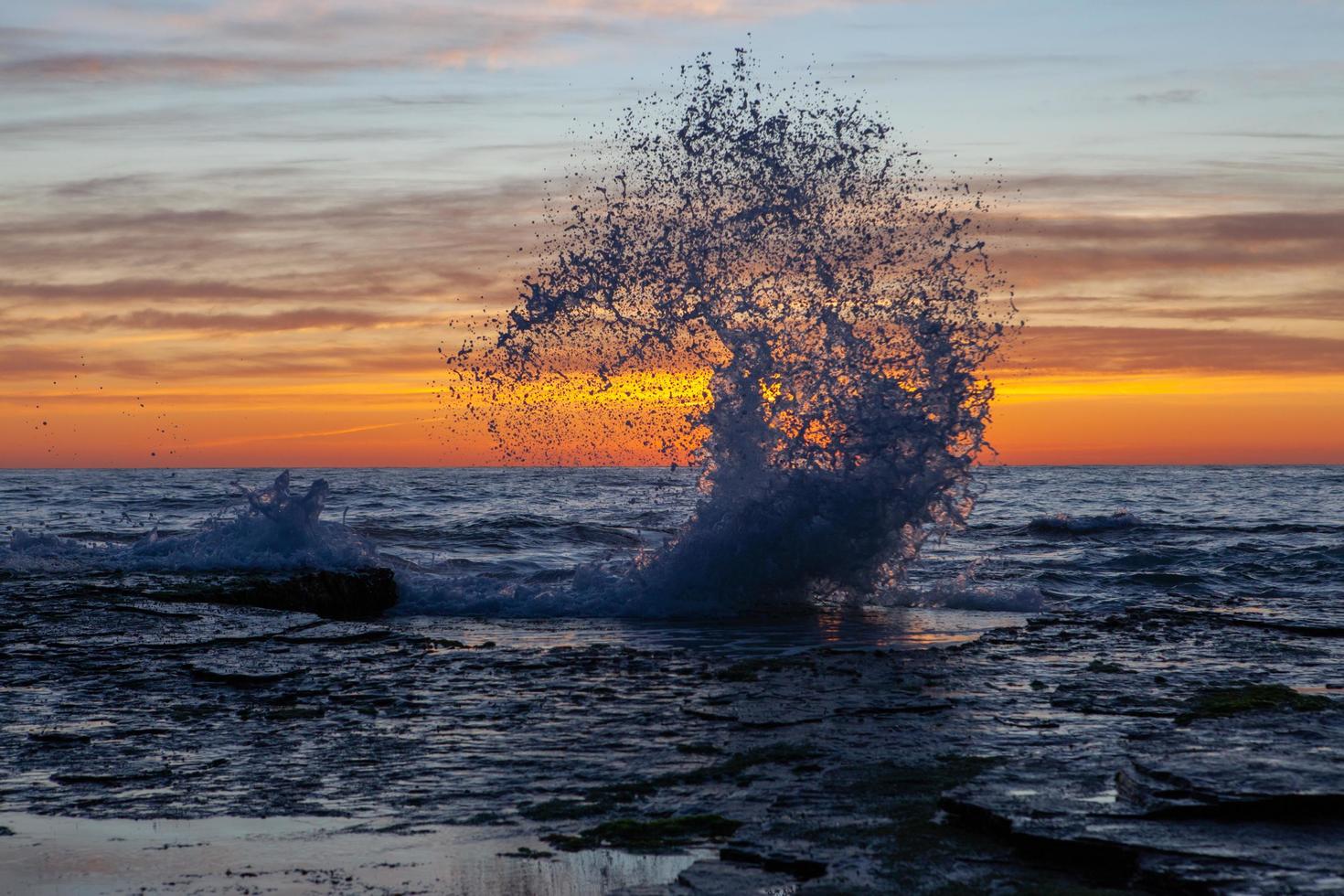 Wellen spritzen bei Sonnenuntergang foto