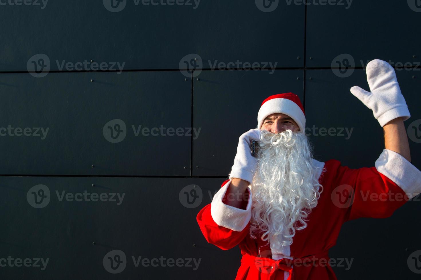 moderner weihnachtsmann, der am telefon spricht. Bestellung der Dienste eines Animateurs für Weihnachten und Neujahr. online-grüße über internet und mobile kommunikation, soziale distanz foto