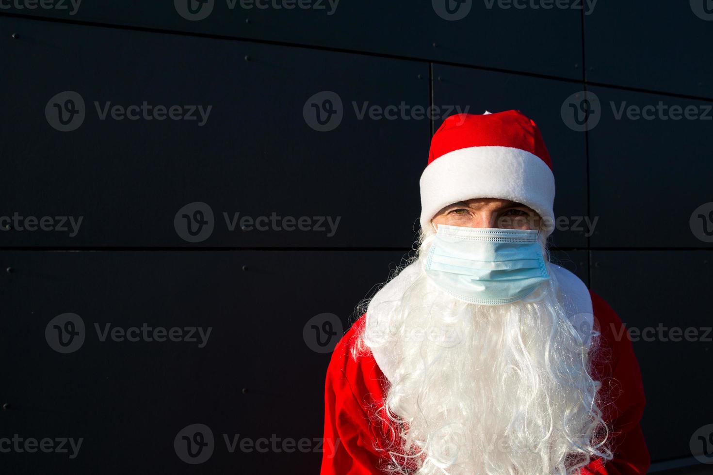 weihnachtsmann mit weißem bart im roten mantel in einer medizinischen maske. weihnachten in der coronavirus-pandemie, saisonale krankheiten, sars und lungenentzündung in den ferien. Schutz vor Viren im neuen Jahr foto