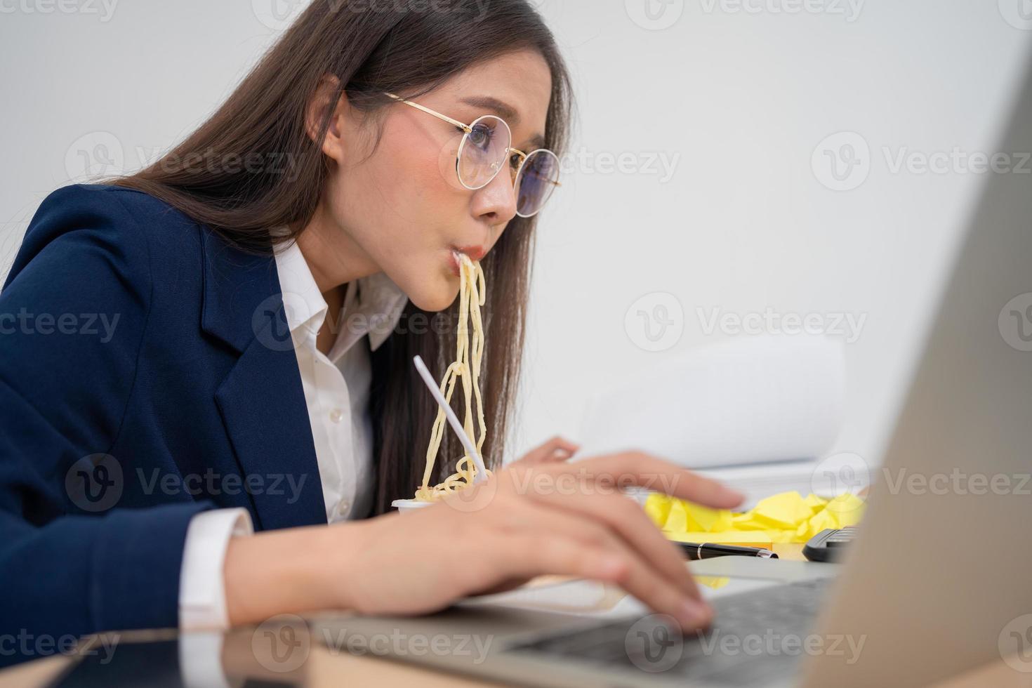 Beschäftigte und müde Geschäftsfrau, die Spaghetti zum Mittagessen im Büro isst und daran arbeitet, einem Chef Jahresabschlüsse zu liefern. überarbeitet und ungesund für Fertiggerichte, Burnout-Konzept. foto