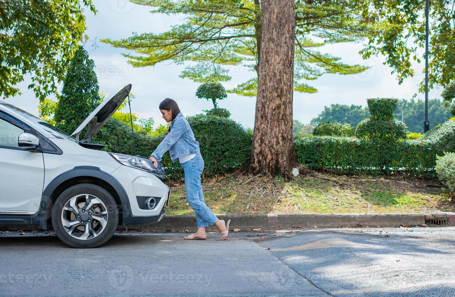 Wütende asiatische Frau, die nach einer Autopanne auf der Straße um Hilfe ruft. konzept des fahrzeugmotorproblems oder unfall- und notfallhilfe durch einen professionellen mechaniker foto