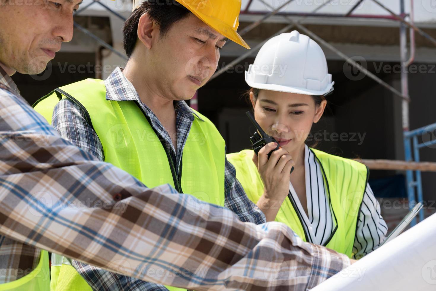 asiatische ingenieurin oder junge architektin setzen aus sicherheitsgründen einen helm auf und sprechen mit einem auftragnehmer über ein bauwerksprojekt, konzept der teamarbeit, führungskonzept. foto