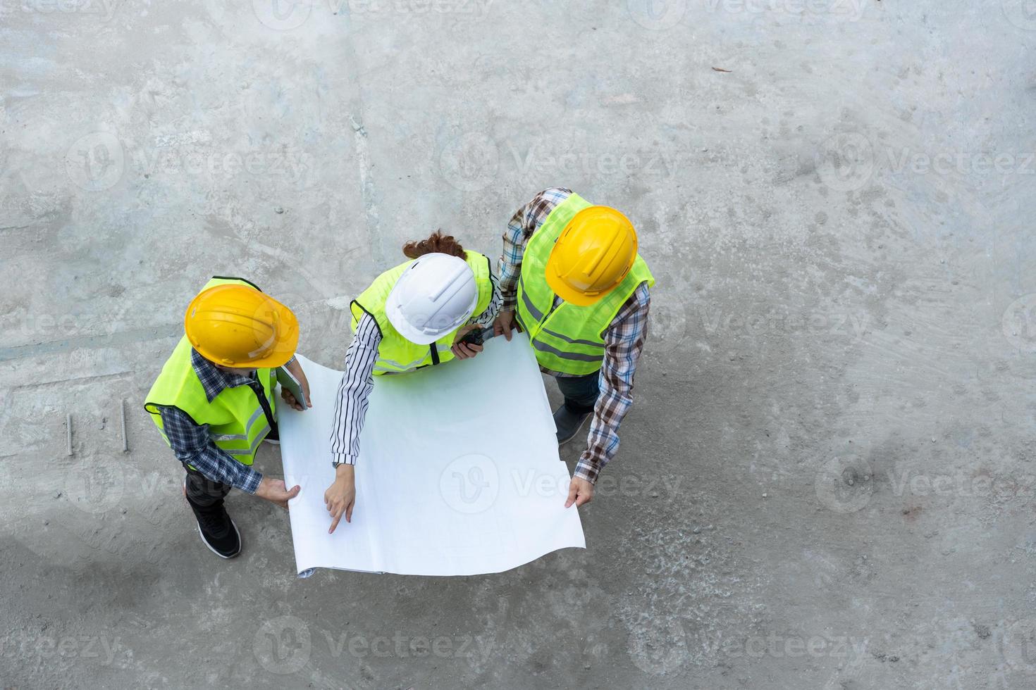 Draufsicht eines asiatischen Ingenieurs oder einer jungen Architektin, die aus Sicherheitsgründen einen Helm aufsetzt und mit einem Auftragnehmer über ein Bauprojekt einer Fabrik spricht, Konzept der Teamarbeit, Führungskonzept. foto