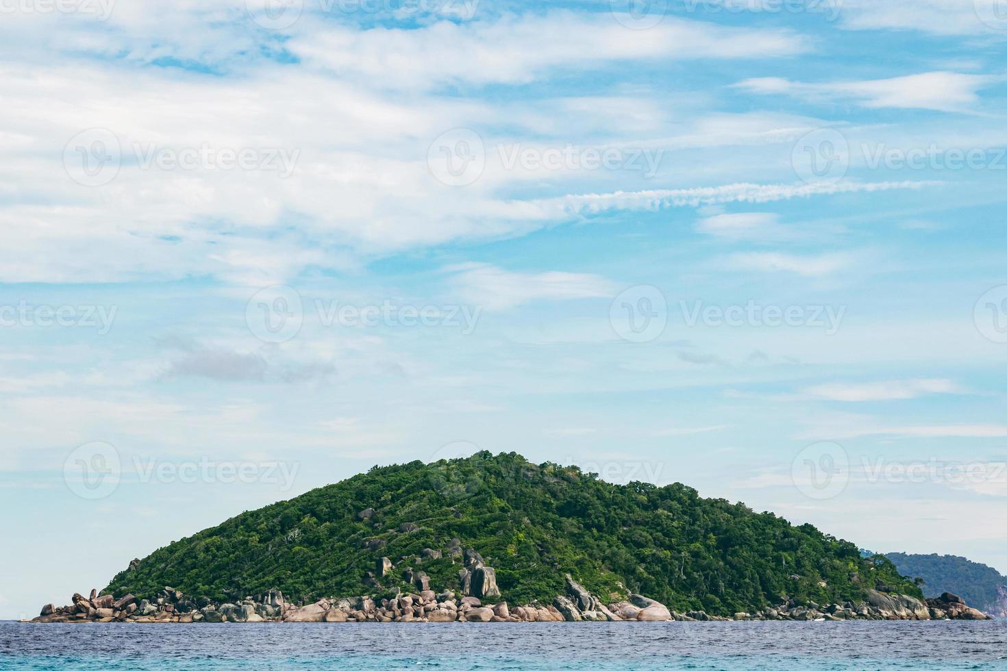 Einsame Insel mit felsiger Küste und tropischem Wald. foto