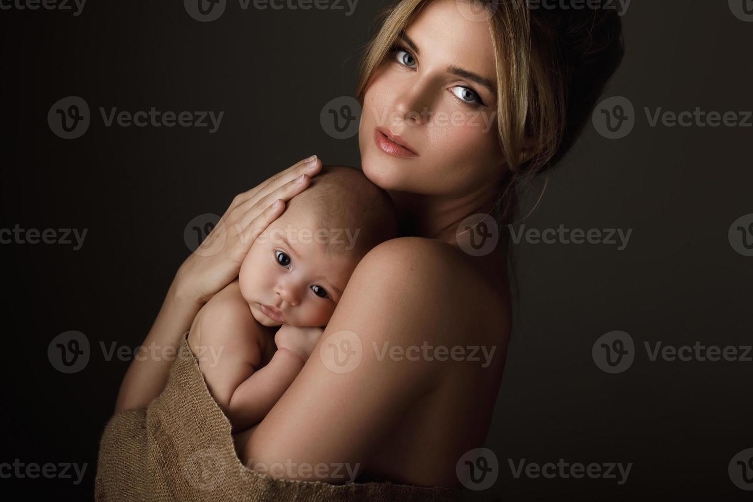 Schöne Mutter und ihr kleines Baby sind in Sackleinen gehüllt foto