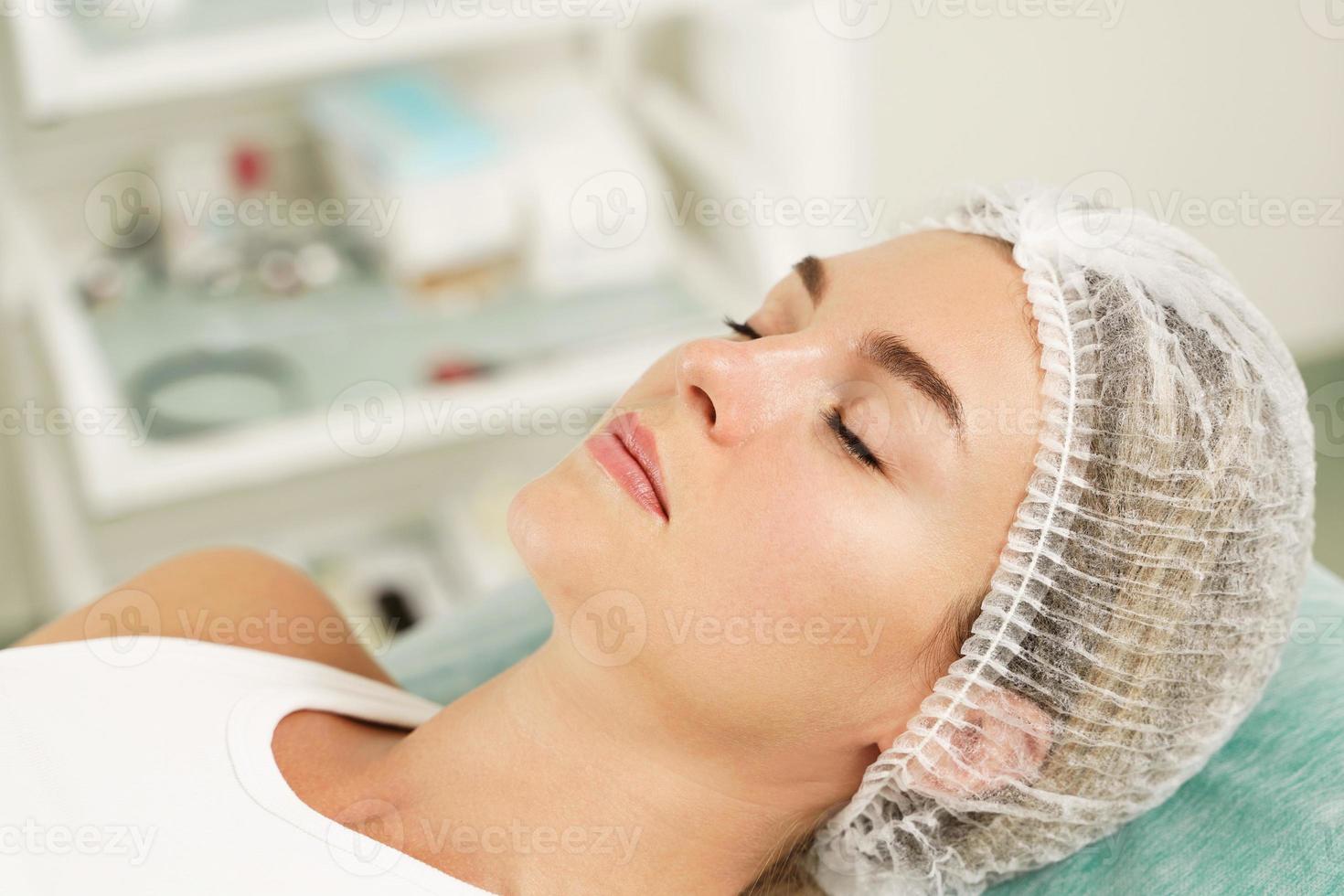 Frau mit sterilem Hut vor der Behandlung in der ästhetischen medizinischen Klinik foto