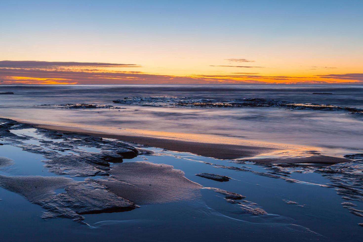 Langzeitbelichtung eines Sonnenuntergangs am Strand foto