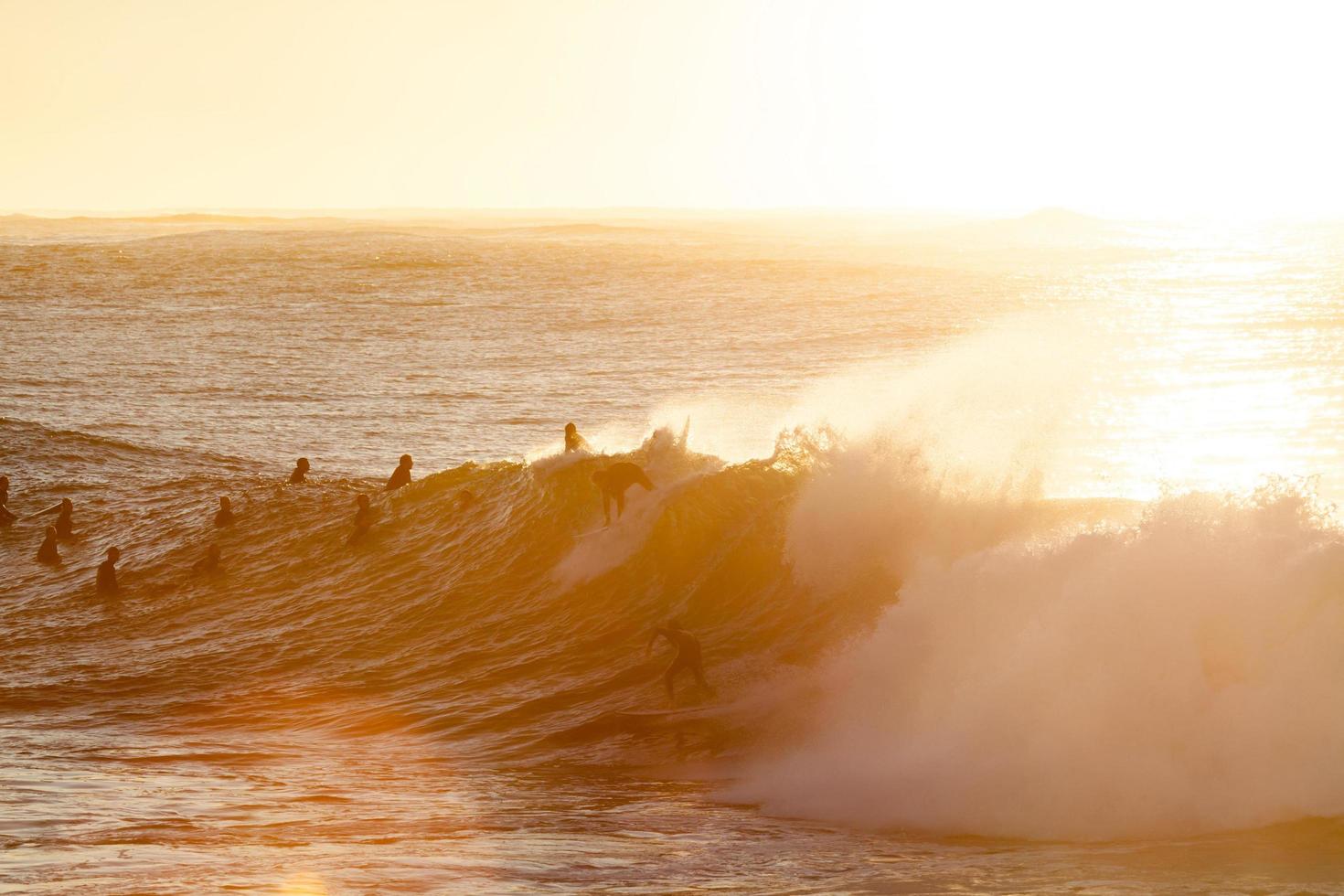 Silhouetten von Menschen, die zur goldenen Stunde surfen foto