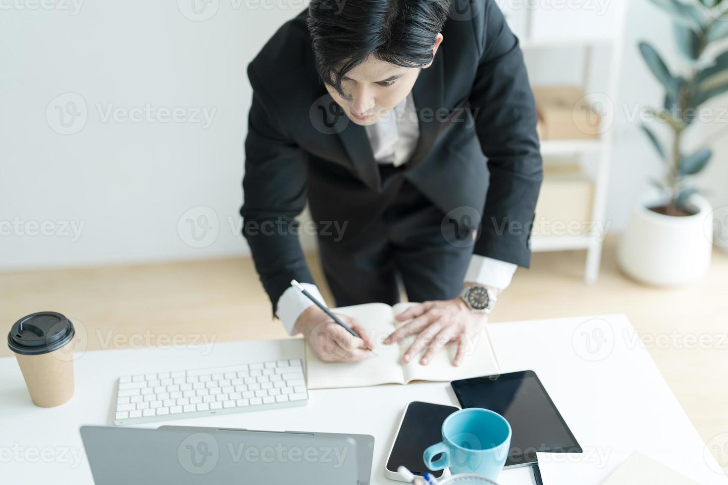 Junger Geschäftsmann, der ein Notizbuch öffnet, um E-Mails von gesendeten Kunden anzuzeigen. und schreibe die Details auf. foto