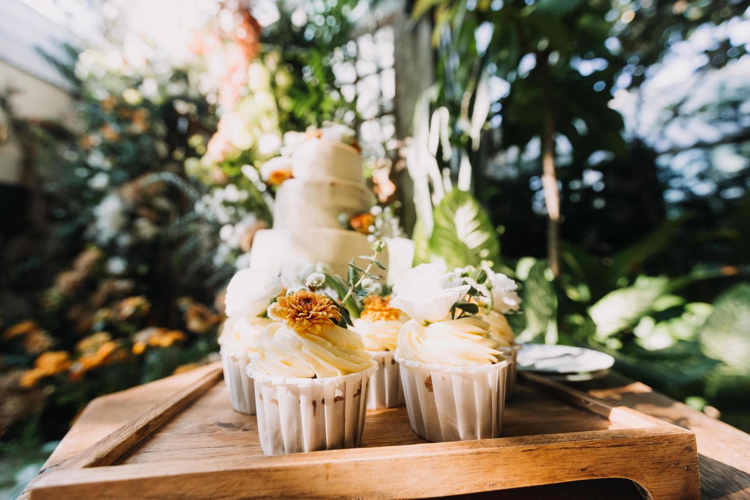 Gourmet-Cupcakes mit weißem Buttercreme-Zuckerguss und Streuseln auf Holzhintergrund foto