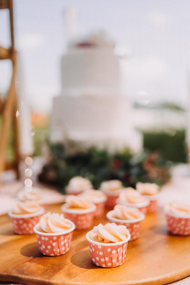 Gourmet-Cupcakes mit weißem Buttercreme-Zuckerguss und Streuseln auf Holzhintergrund foto
