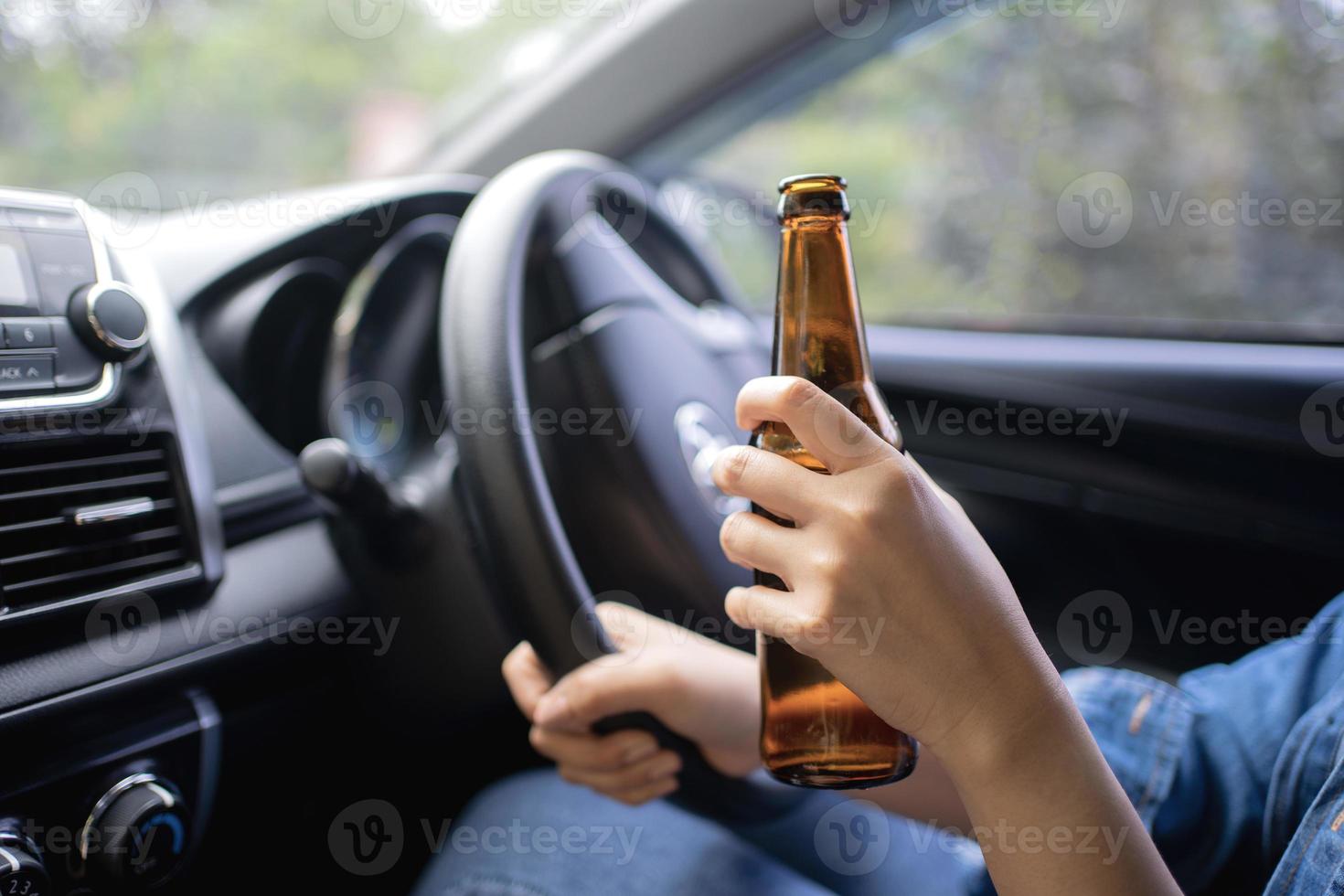 Frau, die beim Autofahren aus einer Bierflasche trinkt, ein Konzept des betrunkenen Fahrens. foto