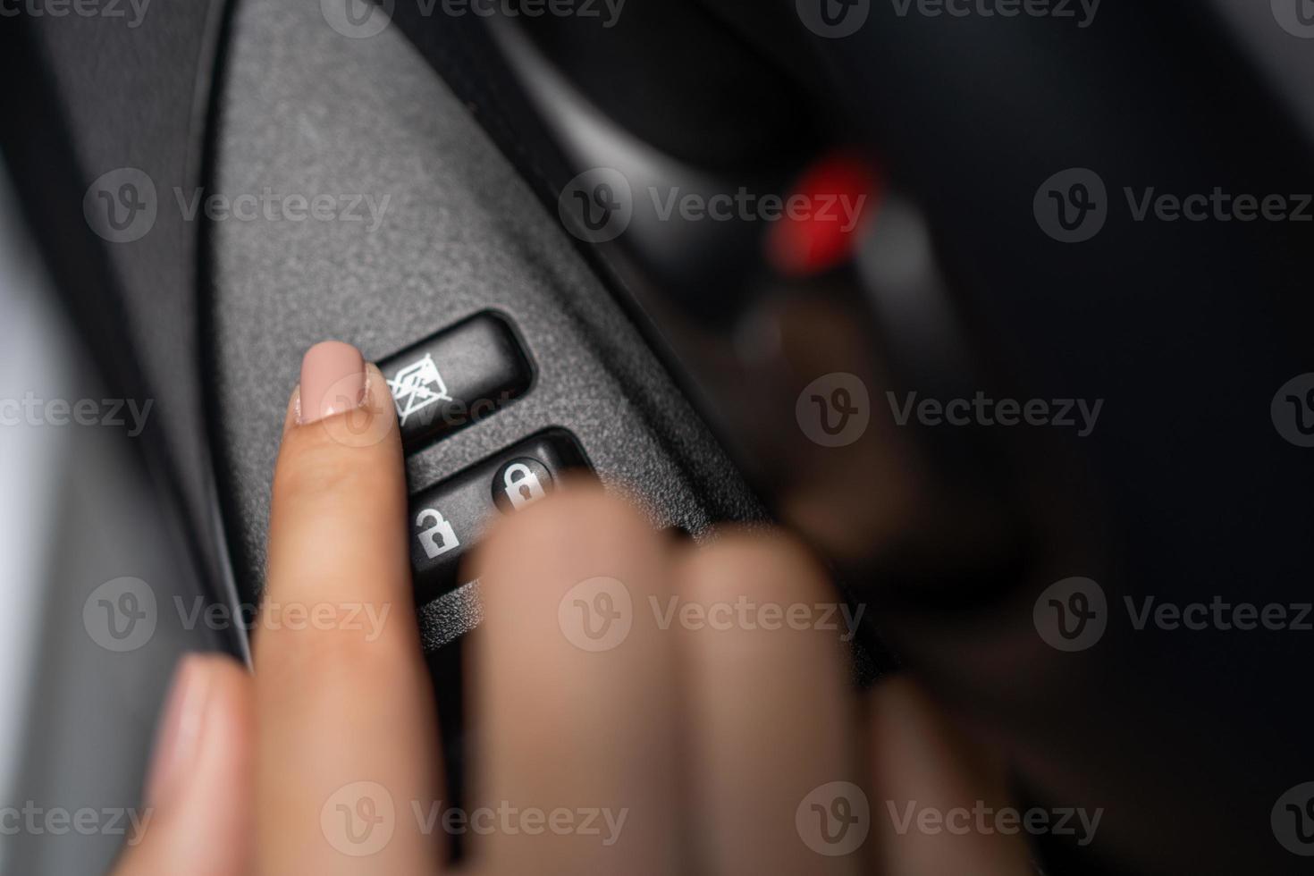 Die Hand einer Frau, die eine Autofensterverriegelungstaste drückt foto