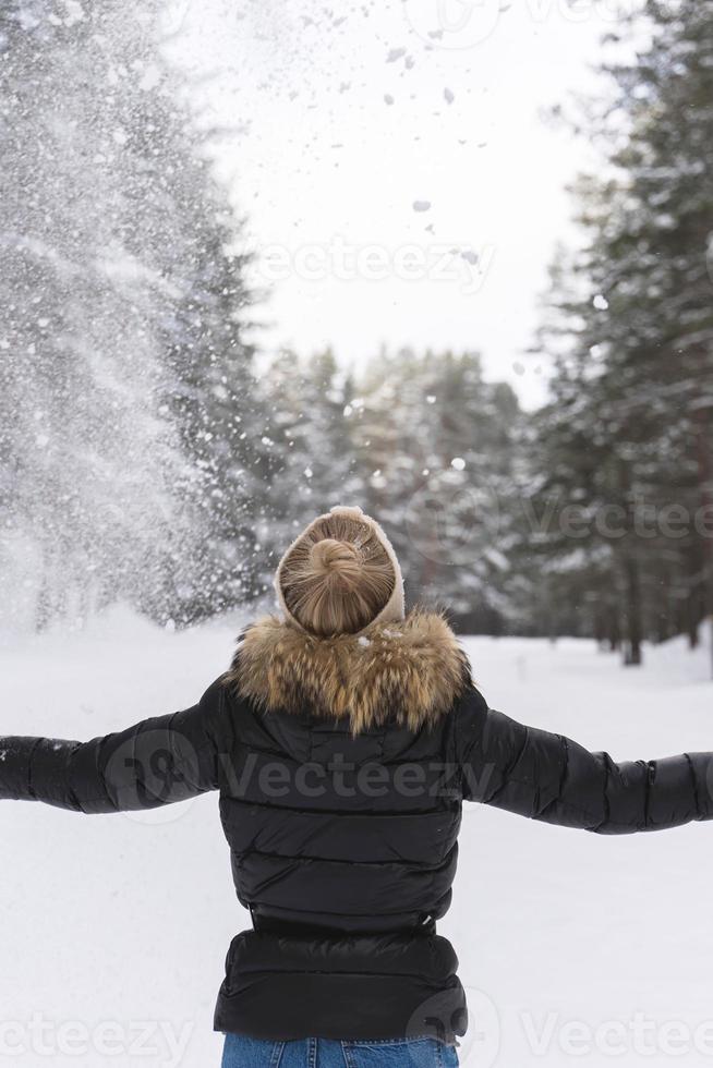 Frau, die an kalten Wintertagen Schnee in die Luft wirft foto