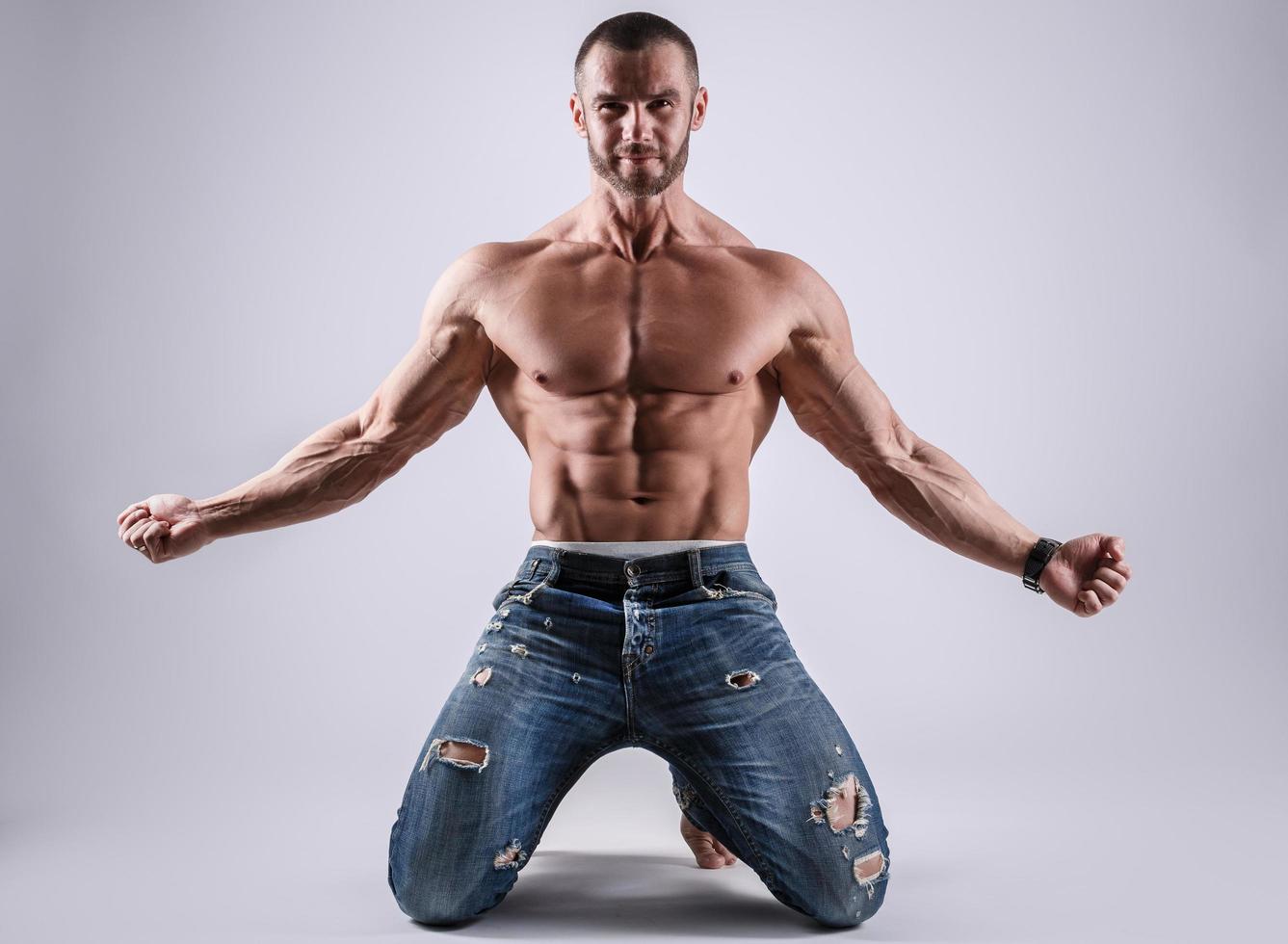 Schöner muskulöser Mann in Jeans, der im Studio posiert foto