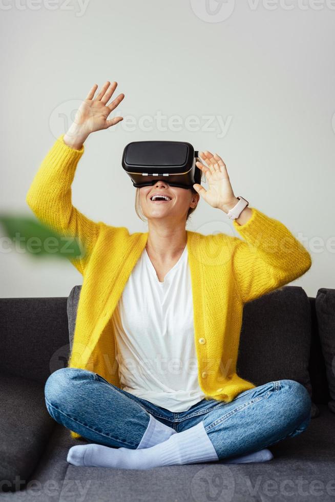 aufgeregte junge sitzen auf dem sofa und verwenden zu hause ein virtual-reality-headset foto