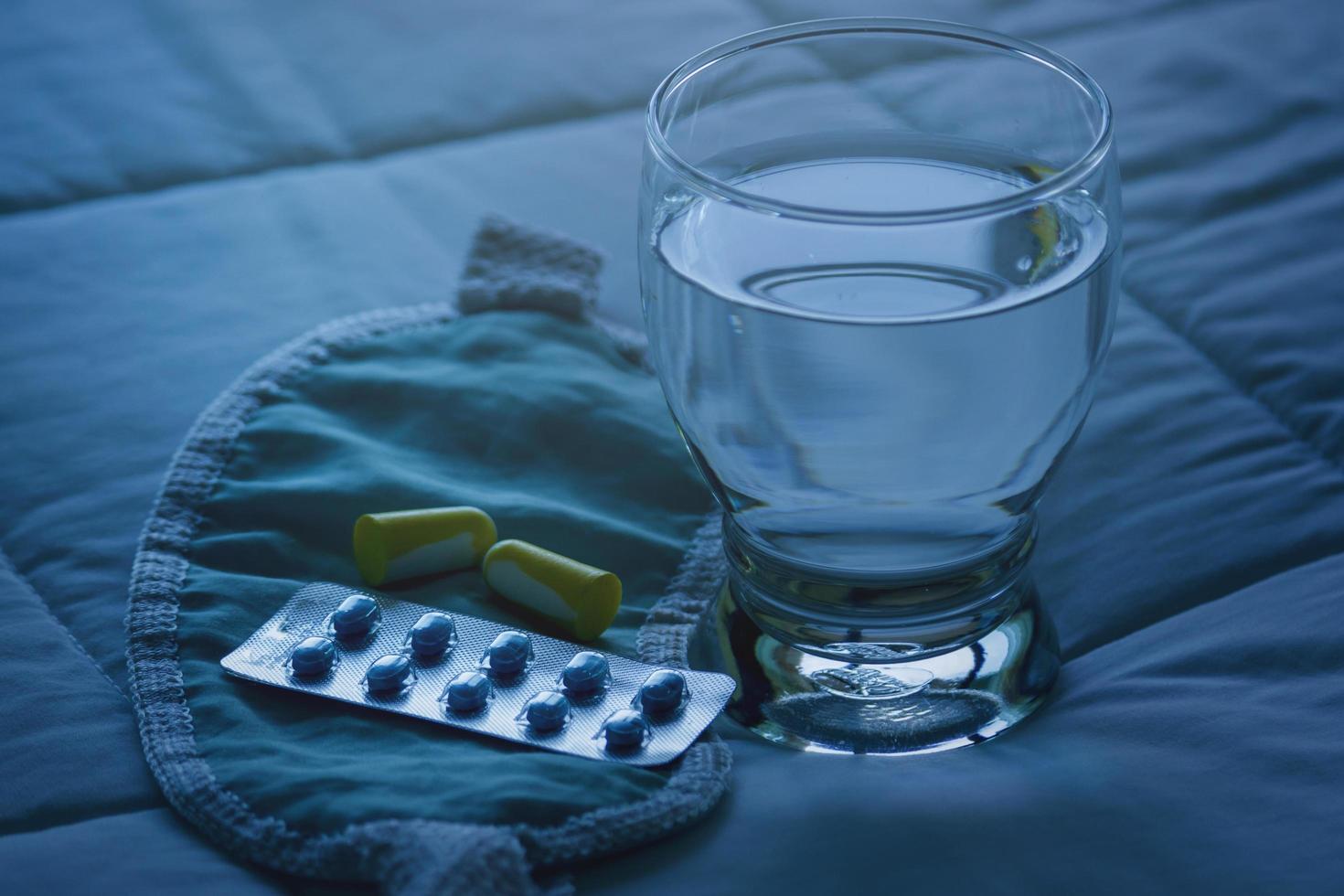 blisterpackung mit schlaftabletten, augenbinde und glas wasser foto