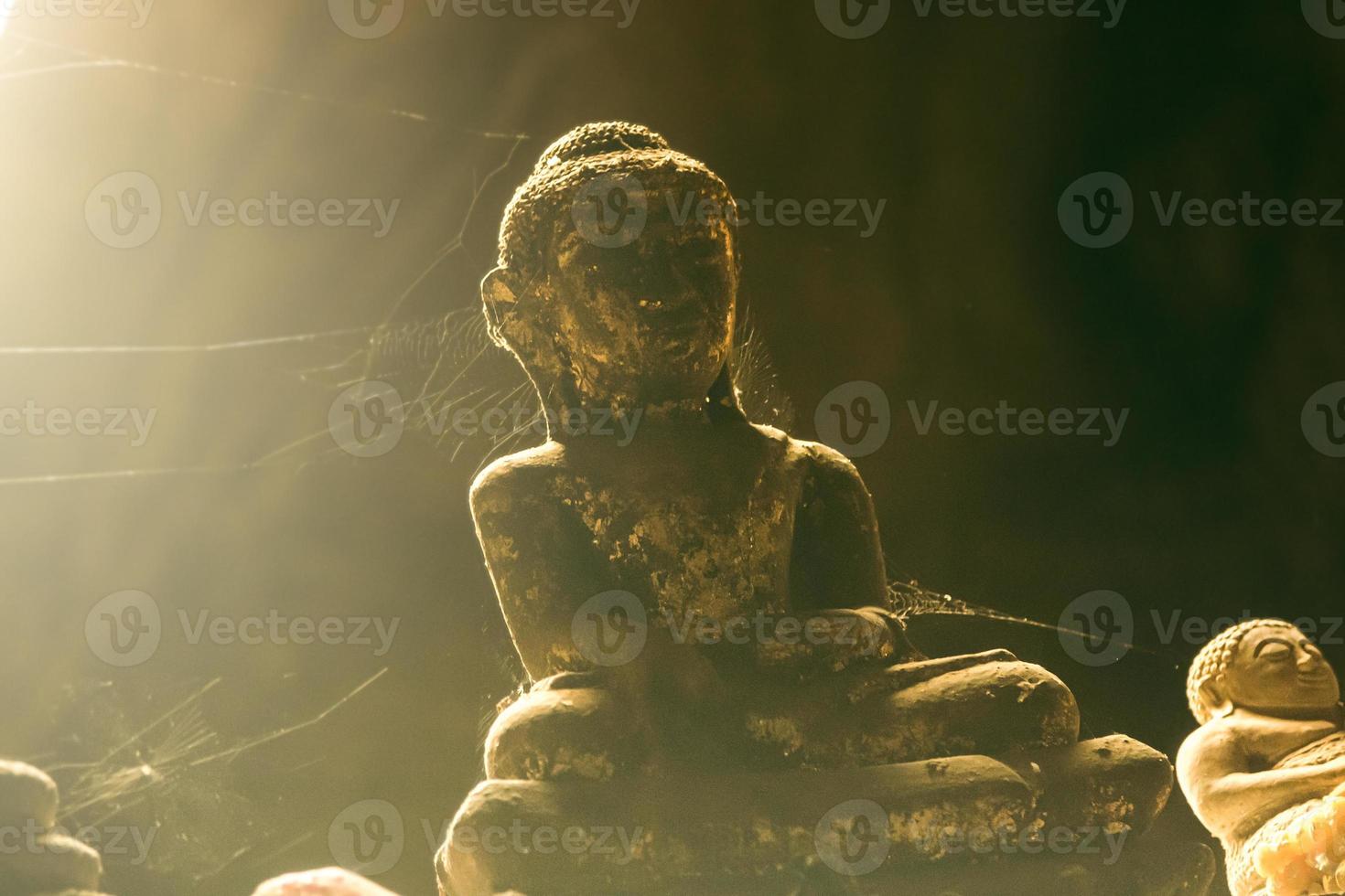 Nahaufnahme von steinernen Buddha-Statuen, die in einem Spinnennetz in einer Höhle bedeckt sind. foto