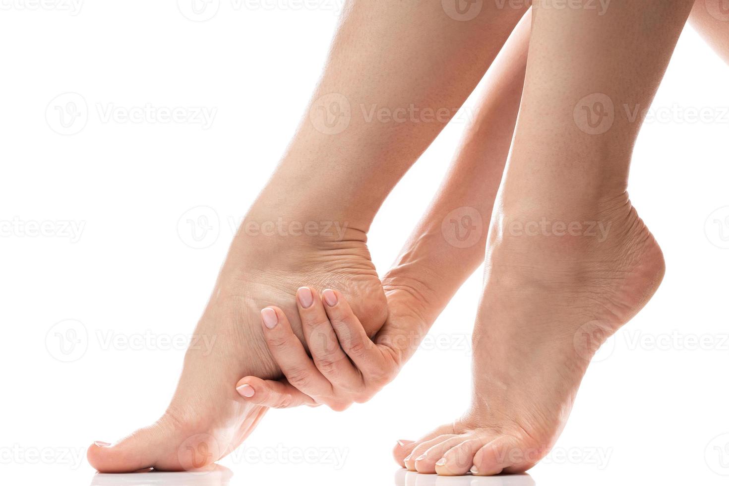 frau, die sanft die weiche haut ihrer ferse berührt. weibliche Füße auf weißem Hintergrund. foto