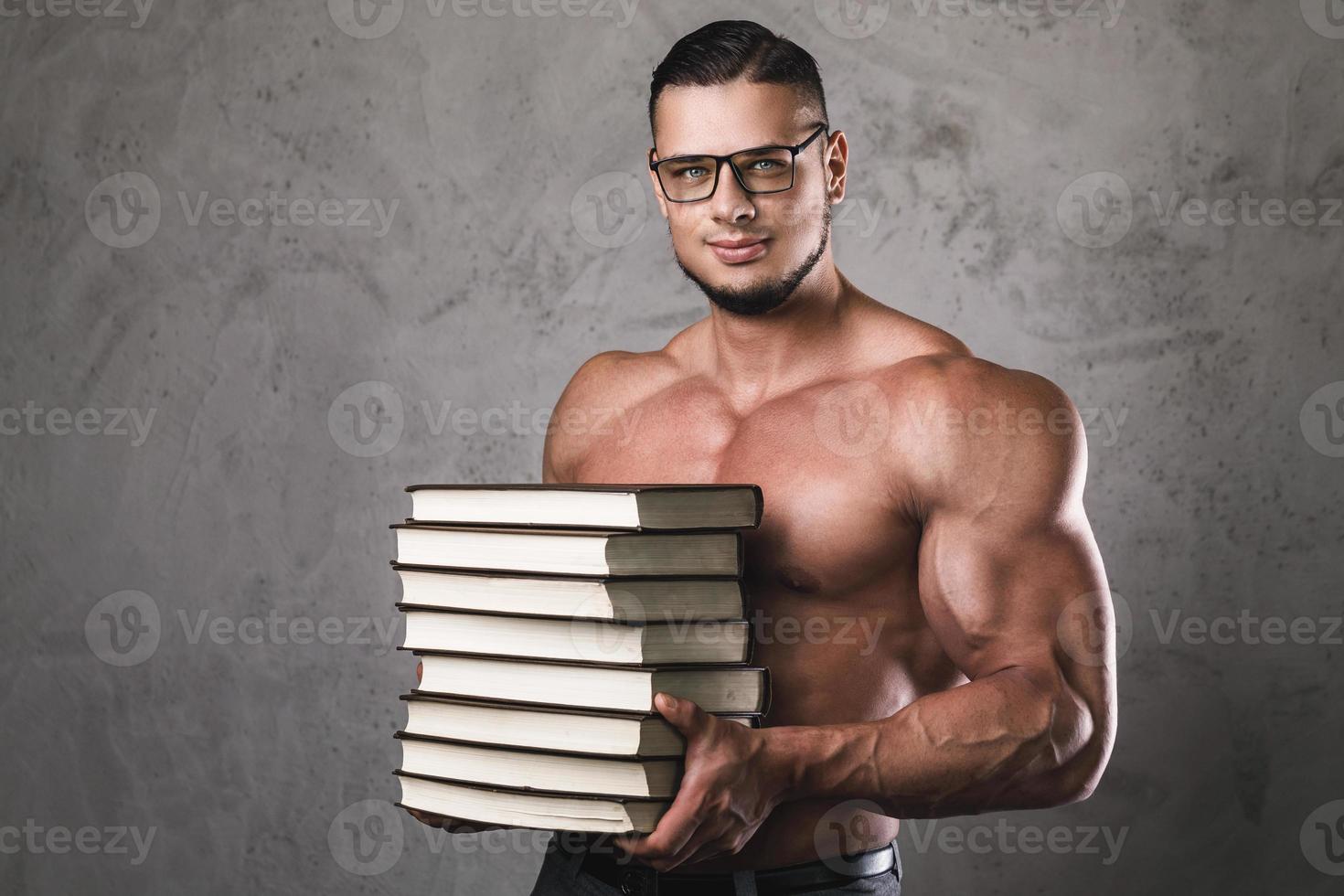 intelligenter und muskulöser Mann mit einem Haufen Bücher foto