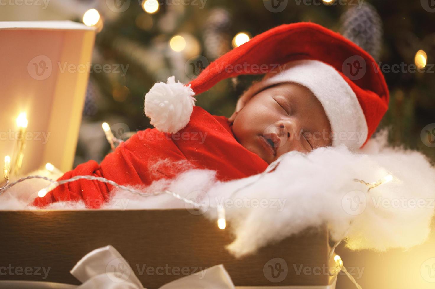 süßes neugeborenes baby mit weihnachtsmannmütze schläft in der weihnachtsgeschenkbox foto