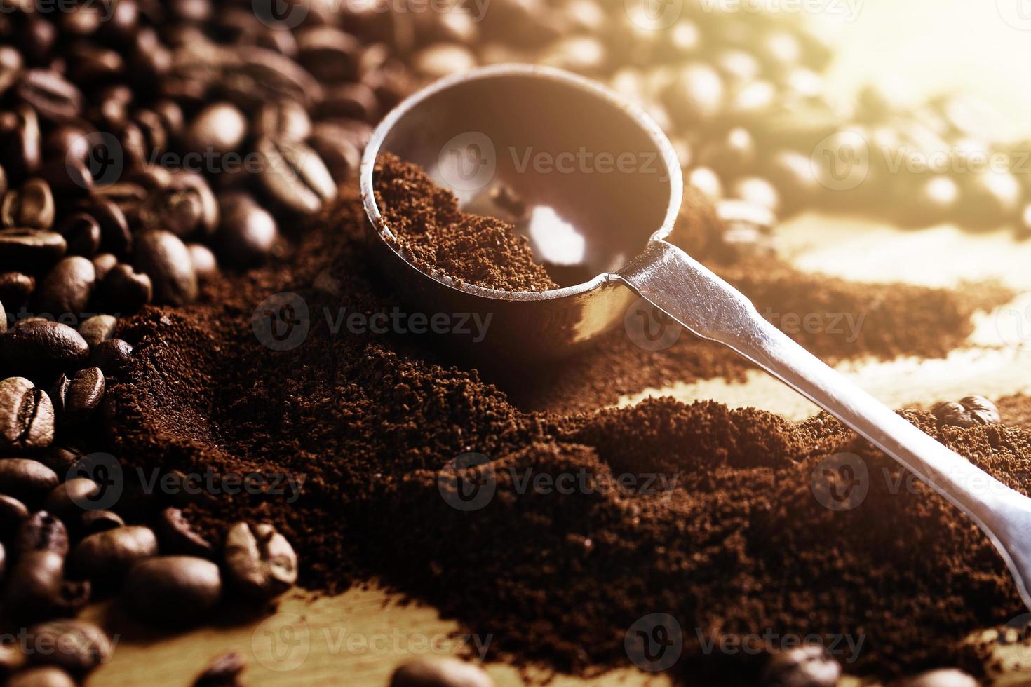 Nahaufnahme von Stahllöffel, gemahlenem Kaffee und Bohnen foto