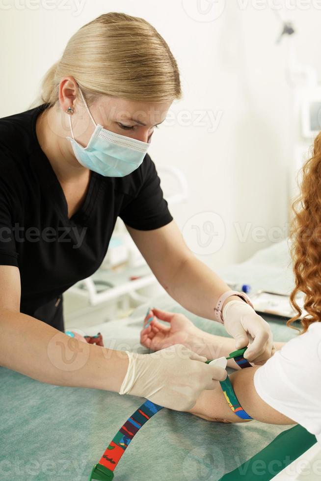 Krankenschwester, die die Blutprobe des Patienten für einen Test oder eine Spende sammelt foto