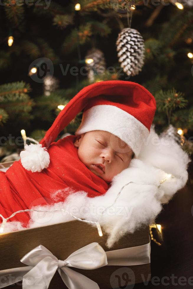 süßes neugeborenes baby mit weihnachtsmannmütze schläft in der weihnachtsgeschenkbox foto