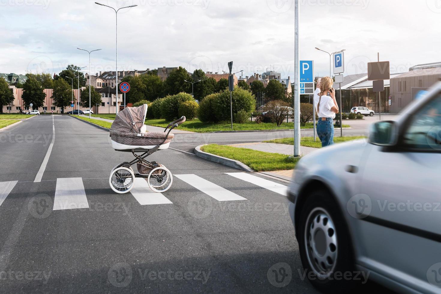 sorglose Mutter telefoniert, während ihr Kinderwagen auf die Straße rollt foto
