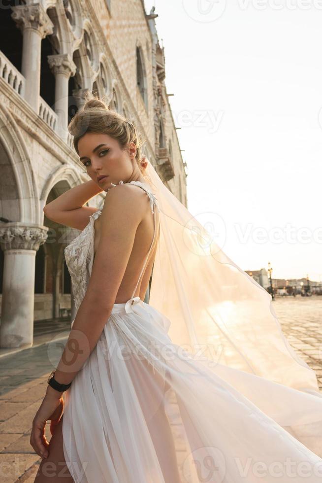 frau, die schönes weißes kleid trägt, das auf einer straße der venedig-stadt geht foto