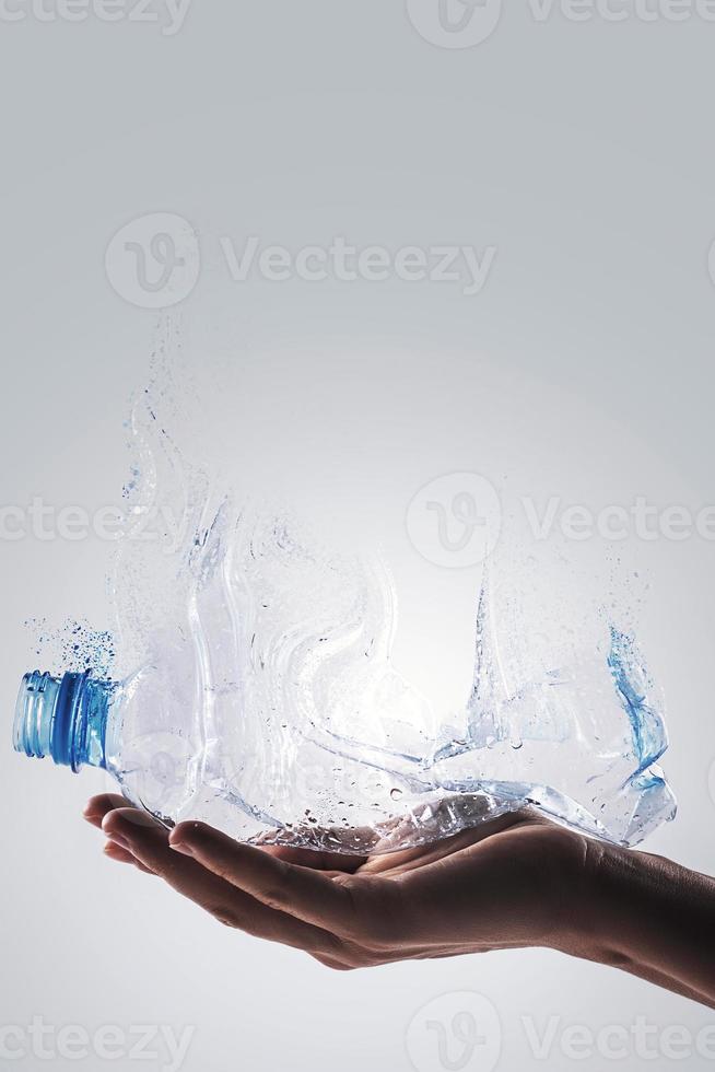 Hand mit gebrauchter Plastikflasche und Dispersionseffekt. Konzept des Kunststoffrecyclings. foto