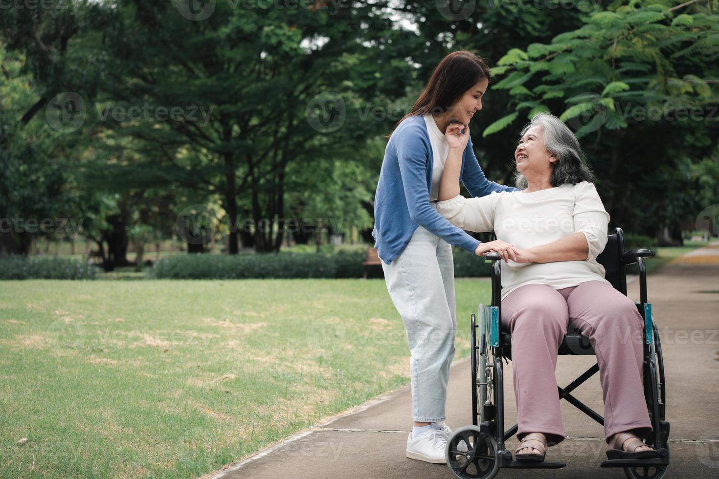 asiatische Pflegekraft oder Krankenschwester, die sich um den Patienten im Rollstuhl kümmert. Konzept des glücklichen Ruhestands mit Betreuung durch eine Pflegekraft und Spar- und Seniorenkrankenversicherung, eine glückliche Familie foto