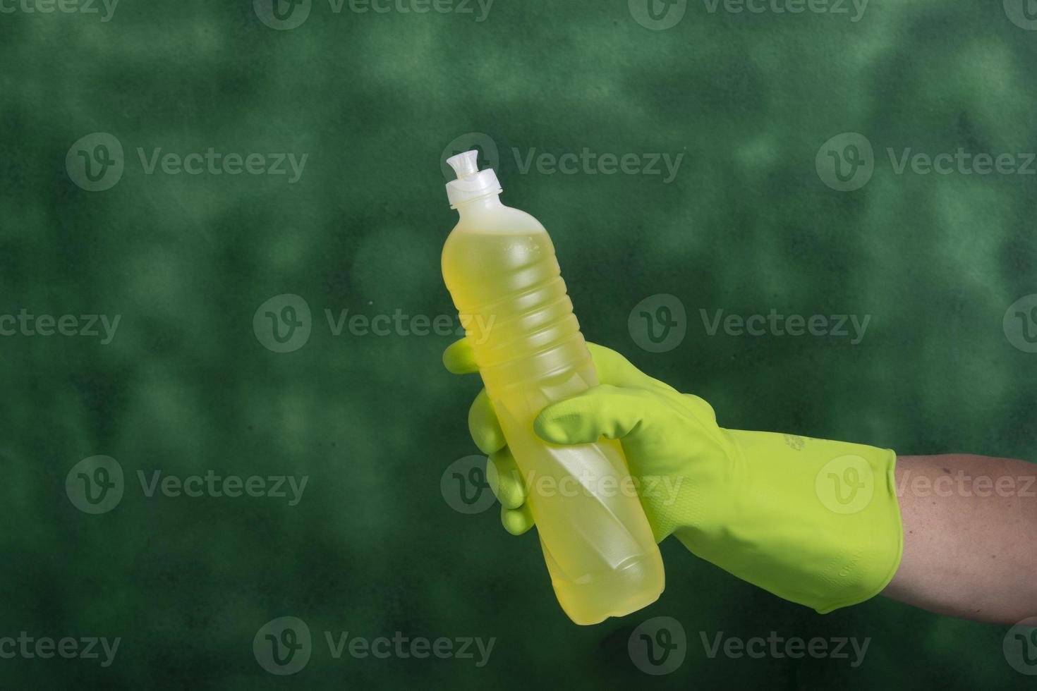 hand mit schutzhandschuh, der verpackungen von reinigungsprodukten hält, die für die haushaltshygiene verwendet werden foto
