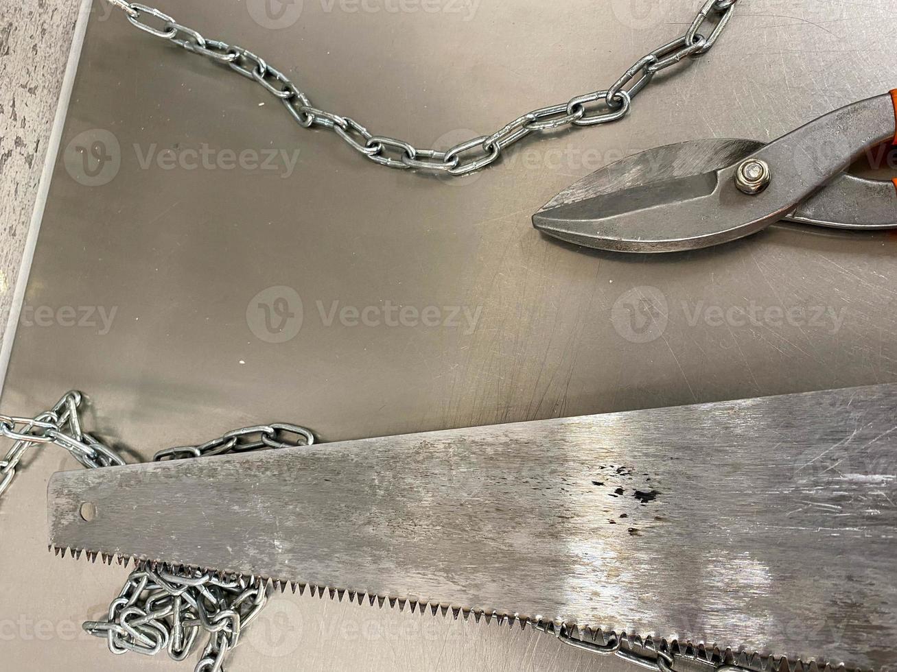 große eisenscharfe metallscheren, metallschneider und eine säge mit ketten liegen auf einem eisentisch. Handschlosserwerkzeuge. der Hintergrund foto