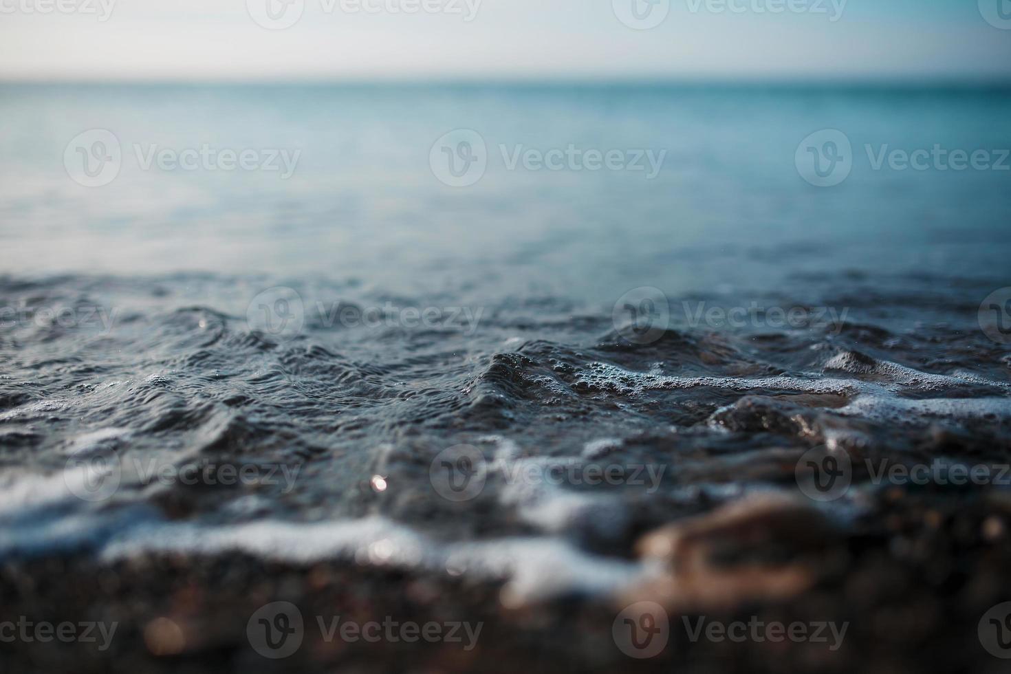 Meereswellen des blauen Meeres mit Schaum rollen am goldenen Ufer an Land. Nahansicht foto