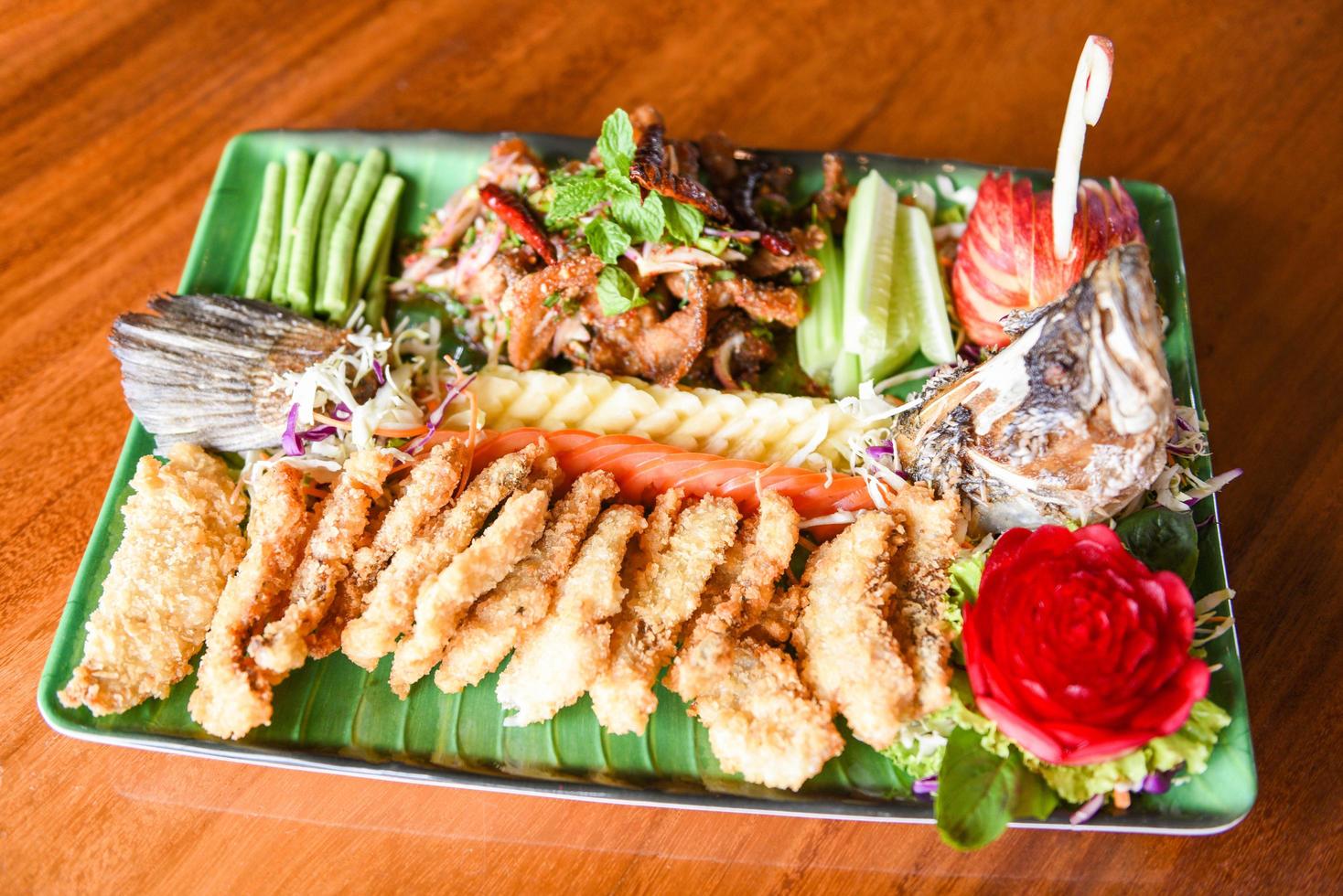 Wolfsbarsch Fischfilet gekochtes Essen im thailändischen Stil asiatisch - Salat Wolfsbarsch gebratener Fisch knusprig dekoriert auf Teller serviert auf Holztisch Essen Abendessen foto