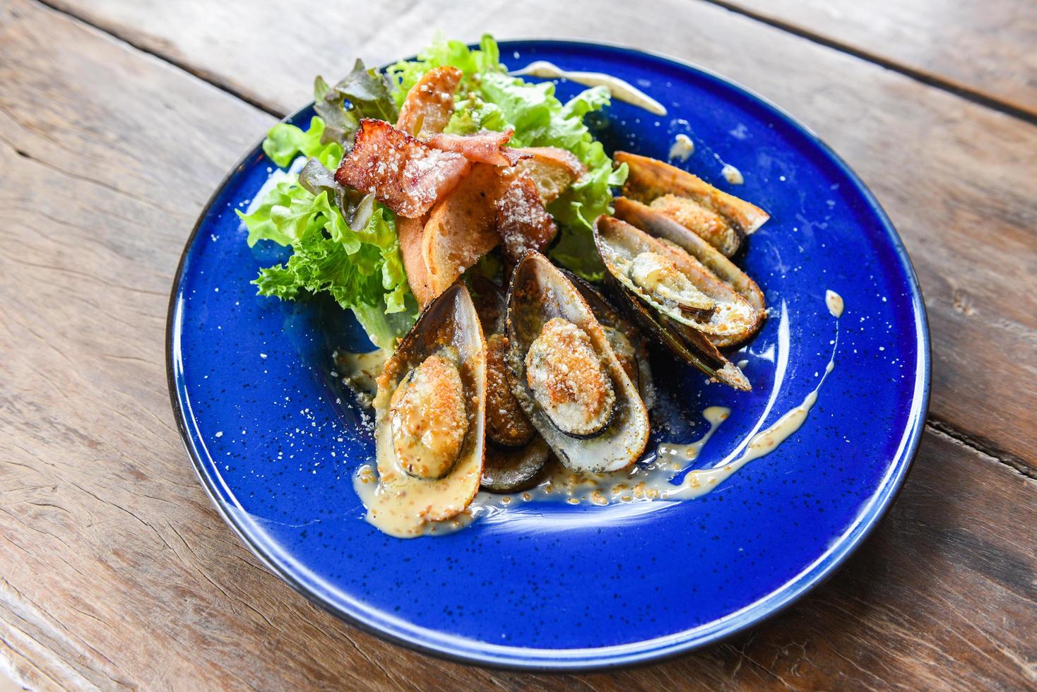 gegrillte Muschelschale Schinken Gemüse und Sauce Meeresfrüchte auf dem Tisch serviert - Schalentiere Meeresfrüchteplatte frische Muscheln mit Käse gebacken Abendessen gekocht foto