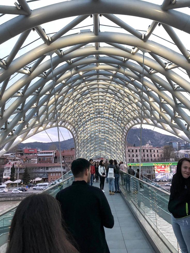 Menschen gehen entlang einer modernen futuristischen Fußgängerbrücke im Stadtzentrum. Georgien, Batumi, 17. April 2019 foto