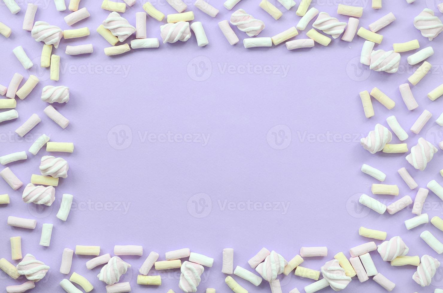 bunter Marshmallow auf violettem Papierhintergrund. pastellkreativer strukturierter rahmen. minimal foto