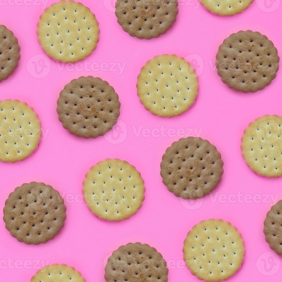 Muster eines braunen Kekses auf einem rosa Hintergrund. trendiges minimales konzept von essen und dessert. abstrakte flache Lage, Draufsicht foto