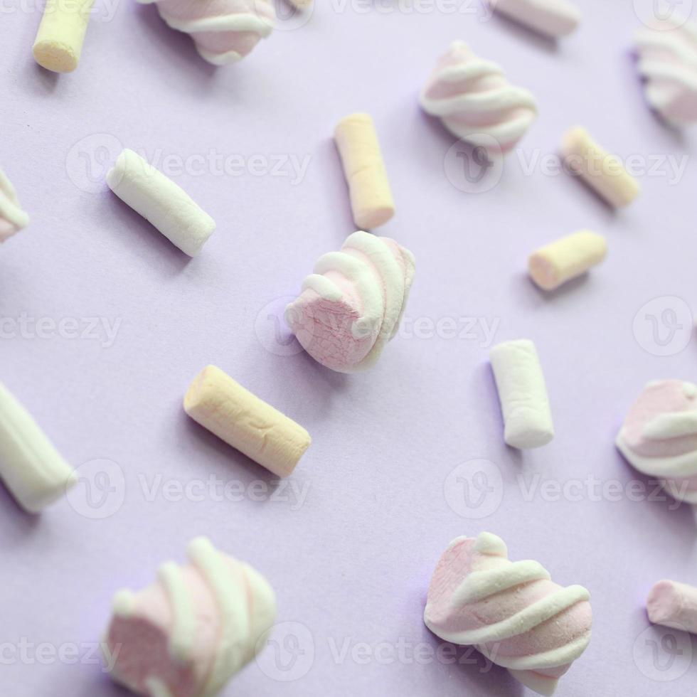 bunter Marshmallow auf violettem Papierhintergrund. pastellfarbenes, kreatives Strukturmuster. perspektivische Makroaufnahme foto