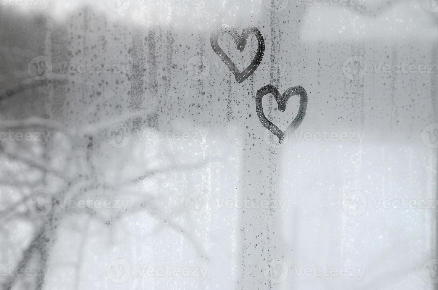 Zwei Herzen, die im Winter auf ein beschlagenes Glas gemalt wurden foto