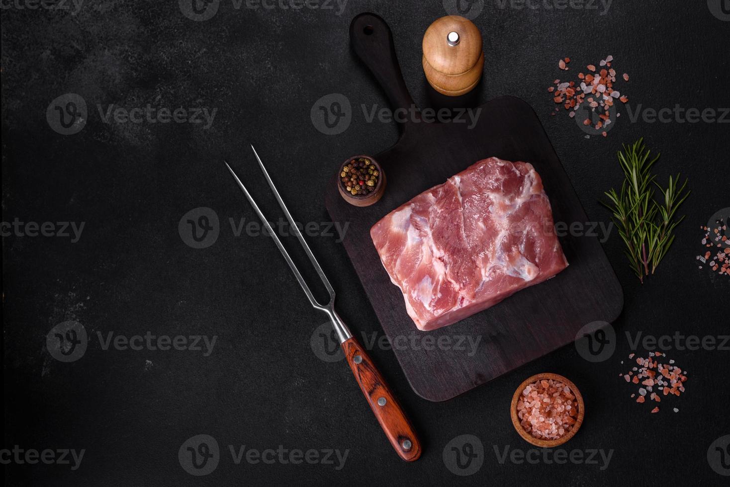 frisches Stück rohes Schweinefleisch mit Gewürzen, Salz und Kräutern auf einem Holzschneidebrett foto