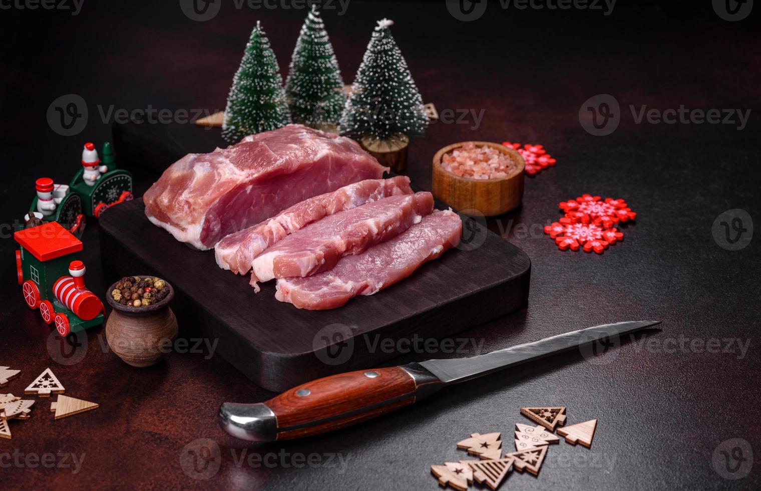 frisches Stück rohes Schweinefleisch mit Gewürzen, Salz und Kräutern auf einem Holzschneidebrett foto