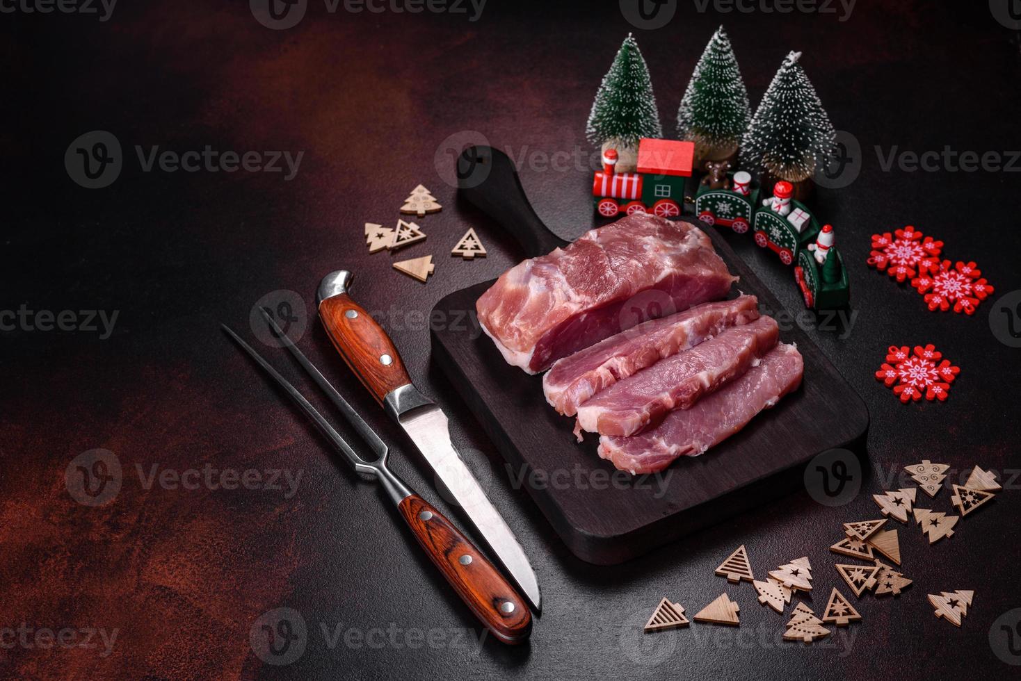 frisches Stück rohes Schweinefleisch mit Gewürzen, Salz und Kräutern auf einem Holzschneidebrett foto