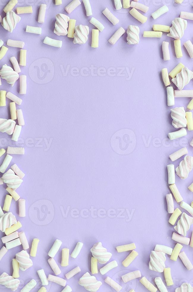 bunter Marshmallow auf violettem Papierhintergrund. pastellkreativer strukturierter rahmen. minimal foto