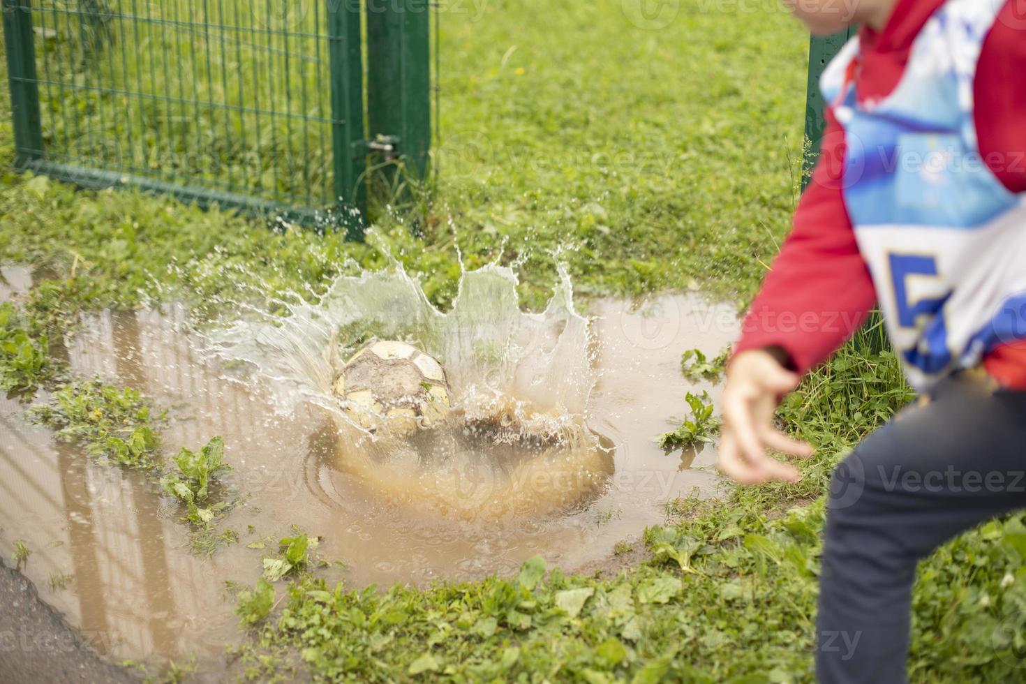 Kind warf Ball in Pfütze. Wasser treffen. Splash-Spiel. foto