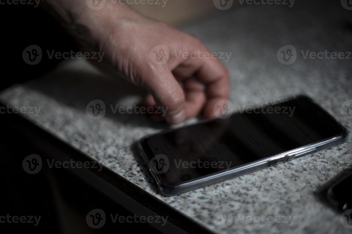 Smartphone auf dem Tisch. Hand greift nach Telefon. foto